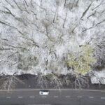 A drónnal készített képen autó az úton egy behavazott erdő mellett Debrecenben 2023. április 7-én.