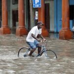 Árvízben álló utcán kerékpározik egy férfi az Idalia hurrikán elvonulása után Havannában 2023. augusztus 29-én.